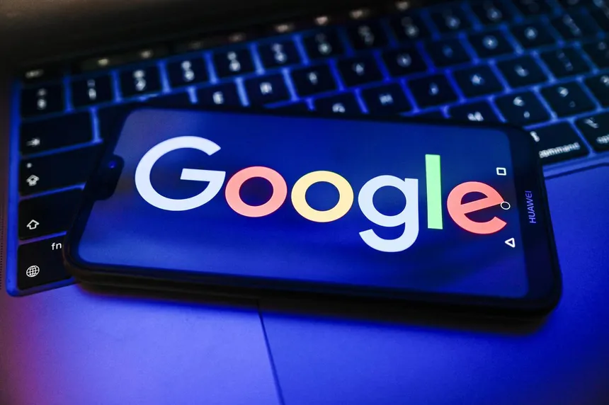 Logo Google visualizzato su smartphone appoggiato sulla tastiera di un laptop